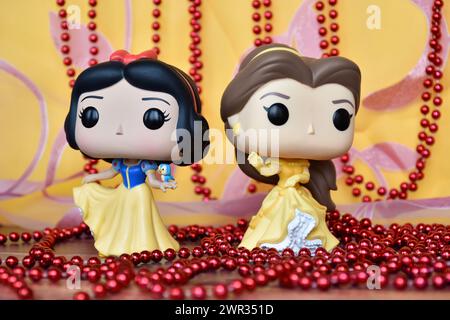 Figurines Funko Pop des princesses Disney Blanche-neige et belle (la beauté et la Bête). Rideau rose doré, collier rouge, fabuleux palais. Banque D'Images