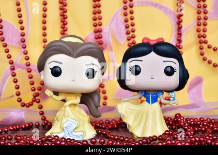 Figurines Funko Pop des princesses Disney belle (belle et la Bête) et Blanche-neige. Rideau rose doré, collier rouge, fabuleux palais. Banque D'Images