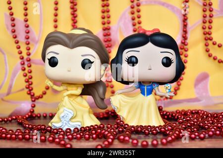 Figurines Funko Pop des princesses Disney belle (belle et la Bête) et Blanche-neige. Rideau rose doré, collier rouge, fabuleux palais. Banque D'Images