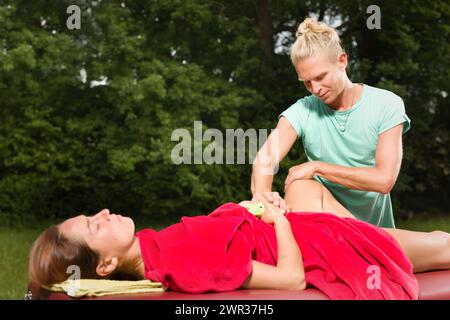 Masseur au travail en donnant massage à la femme en plein air Banque D'Images