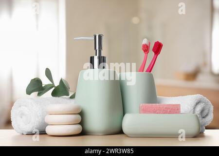 Accessoires de bain. Différents produits de soins personnels et feuilles d'eucalyptus sur table en bois dans la salle de bain Banque D'Images