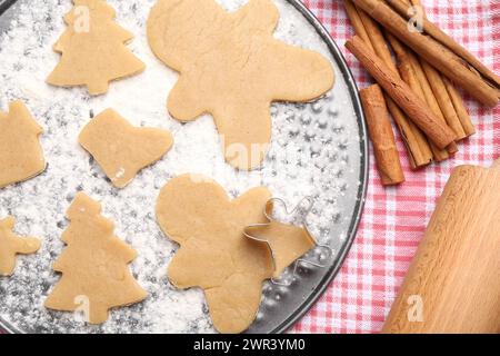 Biscuits de Noël crus dans différentes formes et bâtonnets de cannelle sur la table, pose à plat Banque D'Images