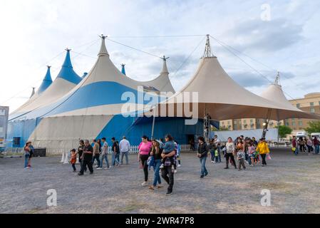 Public sortant de la tente rayée bleue et blanche pour Circus Vasquez, 2024, McAllen, Texas, États-Unis. Banque D'Images