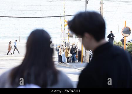 Les touristes prennent des photos autour du passage à niveau de la gare Kamakura Kokomae d'Enoden dans la ville de Fujisawa, préfecture de Kanagawa, le 28 février 2024. Ce passage à niveau est présenté dans la célèbre série d'animation japonaise 'Slam Dunk'. C'est une destination touristique populaire pour les touristes nationaux et étrangers à visiter et à prendre des photos. Cependant, en raison du grand nombre de touristes visitant le train d'Enoden est devenu extrêmement fréquenté, et les résidents vivant le long de la ligne ont été touchés par le problème du surtourisme. Crédit : Yosuke Tanaka/AFLO/Alamy Live News Banque D'Images