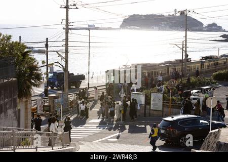Les touristes prennent des photos autour du passage à niveau de la gare Kamakura Kokomae d'Enoden dans la ville de Fujisawa, préfecture de Kanagawa, le 28 février 2024. Ce passage à niveau est présenté dans la célèbre série d'animation japonaise 'Slam Dunk'. C'est une destination touristique populaire pour les touristes nationaux et étrangers à visiter et à prendre des photos. Cependant, en raison du grand nombre de touristes visitant le train d'Enoden est devenu extrêmement fréquenté, et les résidents vivant le long de la ligne ont été touchés par le problème du surtourisme. Crédit : Yosuke Tanaka/AFLO/Alamy Live News Banque D'Images