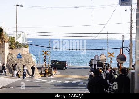 Les touristes prennent des photos autour du passage à niveau de la gare Kamakura Kokomae d'Enoden dans la ville de Fujisawa, préfecture de Kanagawa, le 28 février 2024. Ce passage à niveau est présenté dans la célèbre série d'animation japonaise 'Slam Dunk'. C'est une destination touristique populaire pour les touristes nationaux et étrangers à visiter et à prendre des photos. Cependant, en raison du grand nombre de touristes visitant le train d'Enoden est devenu extrêmement fréquenté, et les résidents vivant le long de la ligne ont été touchés par le problème du surtourisme. Crédit : Yosuke Tanaka/AFLO/Alamy Live News Banque D'Images