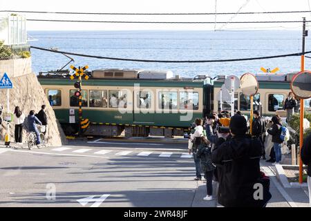 Les touristes prennent des photos autour du passage à niveau de la gare Kamakura Kokomae d'Enoden dans la ville de Fujisawa, préfecture de Kanagawa, le 28 février 2024. Ce passage à niveau est présenté dans la célèbre série d'animation japonaise 'Slam Dunk'. C'est une destination touristique populaire pour les touristes nationaux et étrangers à visiter et à prendre des photos. Cependant, en raison du grand nombre de touristes visitant le train d'Enoden est devenu extrêmement fréquenté, et les résidents vivant le long de la ligne ont été touchés par le problème du surtourisme. Crédit : Yosuke Tanaka/AFLO/Alamy Live News Banque D'Images