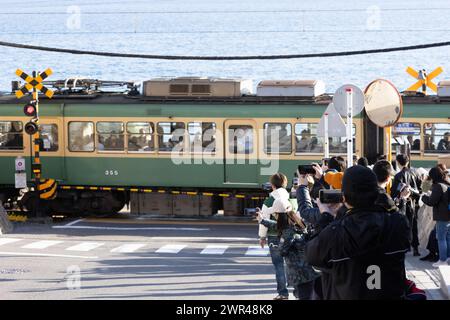 Les touristes prennent des photos autour du passage à niveau de la gare Kamakura Kokomae d'Enoden dans la ville de Fujisawa, préfecture de Kanagawa, le 28 février 2024. Ce passage à niveau est présenté dans la célèbre série d'animation japonaise 'Slam Dunk'. C'est une destination touristique populaire pour les touristes nationaux et étrangers à visiter et à prendre des photos. Cependant, en raison du grand nombre de touristes visitant le train d'Enoden est devenu extrêmement fréquenté, et les résidents vivant le long de la ligne ont été touchés par le problème du surtourisme. Crédit : Yosuke Tanaka/AFLO/Alamy Live News Banque D'Images