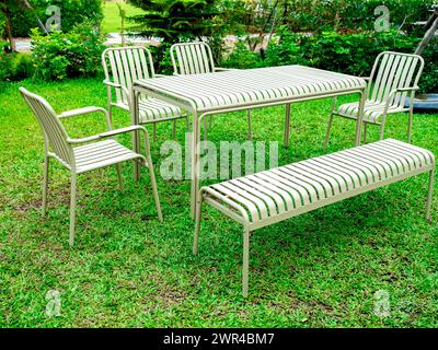 Ensemble de table minimaliste moderne, table, banc et siège de fauteuil, motif de rayures, couleur beige, matériaux en fer sur la décoration d'herbe verte à la backya extérieure Banque D'Images