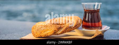 Un verre de thé turc et bagel simit contre la baie de corne dorée à Istanbul, Turquie. BANNIÈRE TURKIYE, FORMAT LONG Banque D'Images