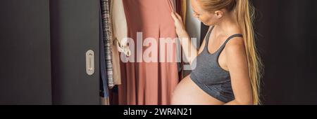 BANNIÈRE, LONG FORMAT Une femme enceinte n'a rien à porter. Une femme enceinte se tient devant un placard avec des vêtements et ne sait pas quoi porter Banque D'Images