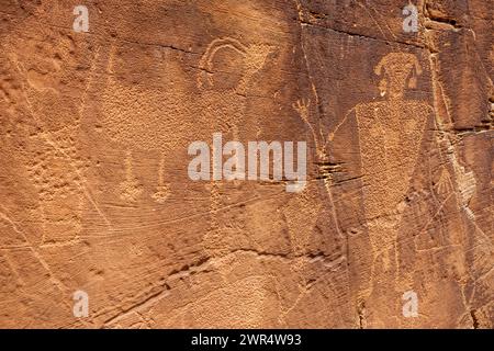 Un panneau de grès avec des figures humaines sculptées, l'une avec un corps large et arrondi, sur de la roche brune au Monument national des dinosaures. Banque D'Images
