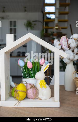 Petite maison de maison confortable avec décor de Pâques avec lapin et oeufs sur la table de la cuisine. Bâtiment, conception, projet, déménagement à la nouvelle maison, hypothèque, insuranc Banque D'Images