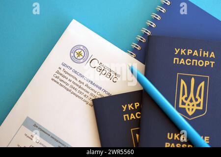 KIEV, UKRAINE - 27 NOVEMBRE 2023 logo du service de passeport avec passeport ukrainien international et stylo sur la table Banque D'Images