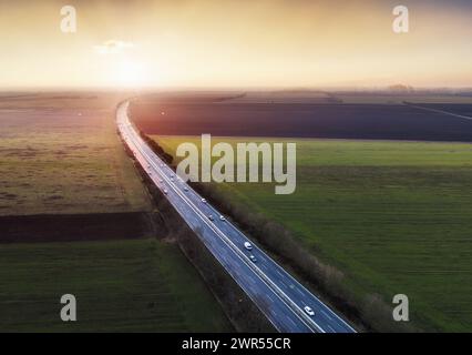 Vue aérienne des camions de transport en conduite à grande vitesse sur une autoroute à travers le paysage rural. Scène de fret sur l'autoroute Banque D'Images