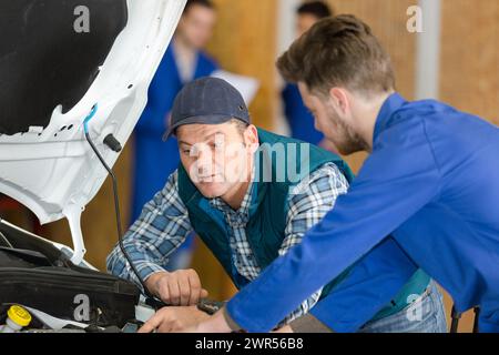 portrait de mécaniciens inspectant le capot du véhicule Banque D'Images