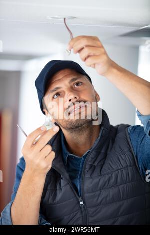 l'homme change une ampoule de projecteur dans le plafond Banque D'Images