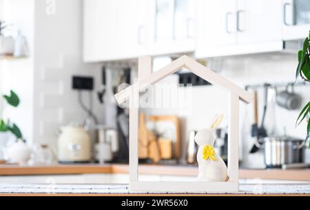 Petite maison de maison confortable avec décor de Pâques avec lapin et oeufs sur la table de la cuisine. Bâtiment, conception, projet, déménagement à la nouvelle maison, hypothèque, insuranc Banque D'Images