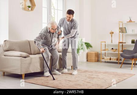 Médecin ou infirmière aidant l'homme senior avec canne à se tenir debout et à marcher Banque D'Images