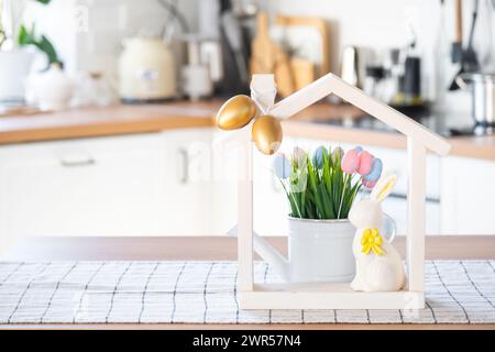Petite maison de maison confortable avec décor de Pâques avec lapin et oeufs sur la table de la cuisine. Bâtiment, conception, projet, déménagement à la nouvelle maison, hypothèque, insuranc Banque D'Images