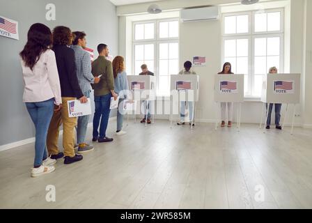 Des gens debout dans une file d'attente avec un bulletin de vote au bureau de vote du centre de vote. Banque D'Images