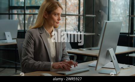 Femme Caucasien adulte freelance femme d'affaires employée femme d'âge moyen secrétaire de femme utilisant l'application moderne d'utilisation de la technologie sans fil. Employé de bureau au bureau Banque D'Images