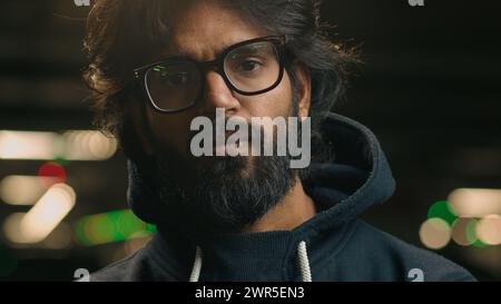 Gros plan portrait sérieux hipster confiant musulman homme arabe Indien barbu homme dans la nuit sombre ville parking urbain souterrain posant à la recherche Banque D'Images