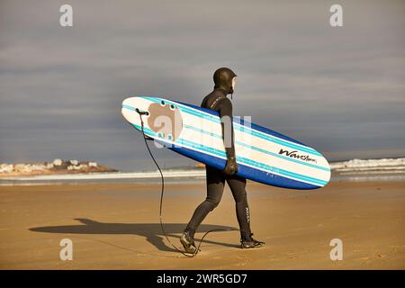 Un surfeur marchant avec sa planche de surf à Good Harbor Beach à Gloucester, Massachusetts Banque D'Images
