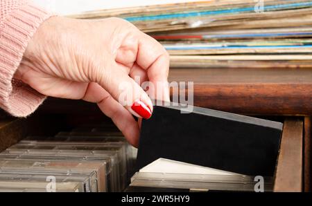 Senior choisissant des cassettes sur des meubles en bois. Banque D'Images