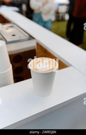 Café latte art dans une tasse de papier blanc Banque D'Images