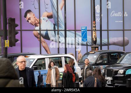 Quelques mois avant les Jeux Olympiques de Paris 2024, les membres du public passent sous une énorme image de la gymnaste de l'équipe GB et ancien médaillé d'or olympique, Max Whitlock devant Coutts Bank sur le Strand, le 7 mars 2024, à Londres, en Angleterre. Coutts Bank (et Natwest Bank) sont actuellement les partenaires officiels de Team GB. Banque D'Images