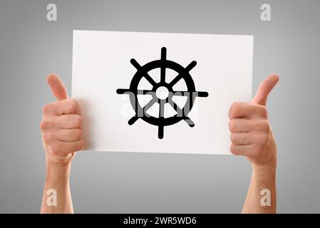Mains d'un homme religieux avec le signe OK tenant une affiche blanche dessinée de roue de dharma gris isolé fond Banque D'Images