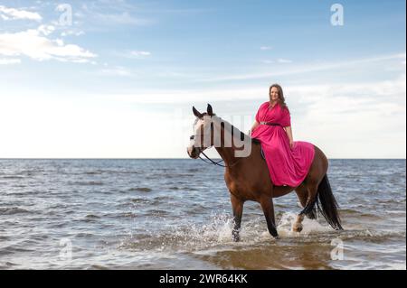 Une femme chevauchant un cheval brun dans l'eau Banque D'Images