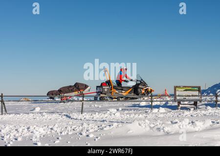 Karpacz, Pologne -10 janvier 2024 : homme du service de sauvetage de montagne avec motoneige avec brancard devant Silesian House dans les montagnes de krkonose. Banque D'Images