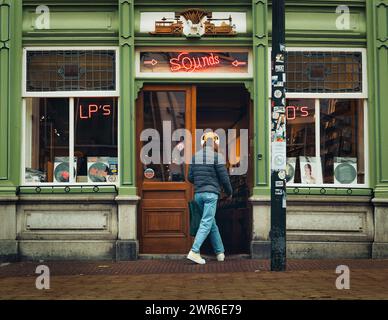 Le client portant des écouteurs entre dans le magasin de musique de Delft Banque D'Images