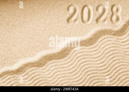 Empreintes de numéros 2028 nouvelle année sur un fond de vagues de sable doré Banque D'Images