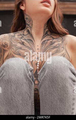 Cette image capture une vue rapprochée d'une zone de poitrine féminine avec un tatouage élaboré et artistique, mettant en évidence les détails et l'artisanat dans n Banque D'Images