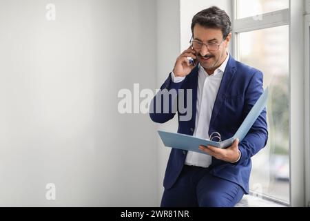 Homme d'affaires d'entreprise dans un costume bleu s'engageant dans une conversation téléphonique Banque D'Images