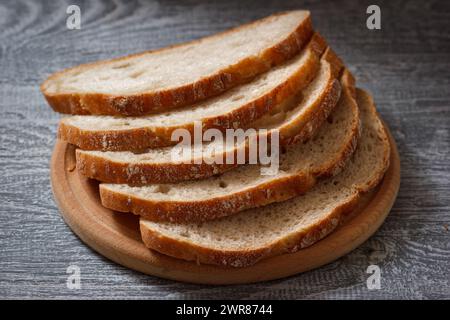 Le pain de seigle foncé tranché sur assiette en bois dans le style rustique. Produit nutritionnel frais et sain. Banque D'Images