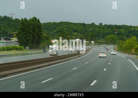 Lyon, France - 7 mai 2023 : les voitures roulent sur une route mouillée après la pluie. La route reflète la lumière des voitures, créant une surface glissante. Banque D'Images