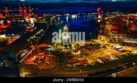 Vue aérienne nocturne d'un port industriel éclairé avec des cargos et des grues au bord de l'eau à Liverpool, Royaume-Uni. Banque D'Images