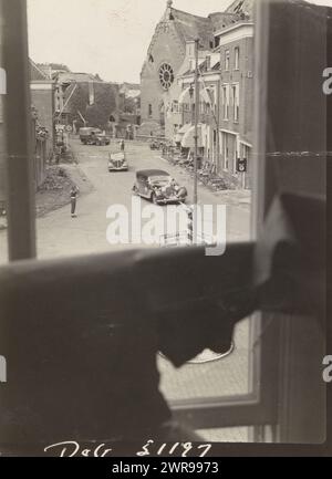 Destruction dans une ville, vue d'une rue avec des bâtiments détruits depuis une fenêtre. Il y a quelques voitures qui roulent dans la rue et un suspect. Soldat anglais vu saluant., anonyme, pays-Bas, 1940 - 1950, support photographique, hauteur 11 cm × largeur 8 cm, photographie Banque D'Images