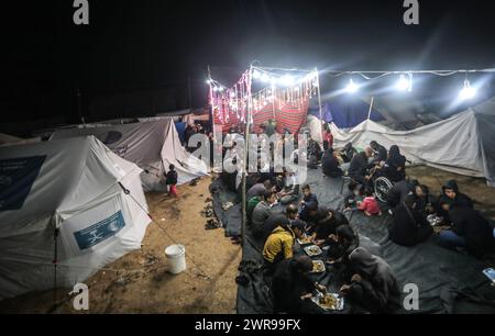 Rafah, Gaza. 11 mars 2024. Les Palestiniens déplacés ont un dîner de rupture rapide (iftar) au milieu de tentes de fortune dans le camp de réfugiés de Rafah, le premier jour du Ramadan du mois sacré des musulmans à Rafah, Gaza, le 11 mars 2024. Photo de Ismael Mohamad/UPI crédit : UPI/Alamy Live News Banque D'Images