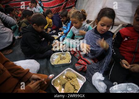 Rafah, Gaza. 11 mars 2024. Les Palestiniens déplacés ont un dîner de rupture rapide (iftar) au milieu de tentes de fortune dans le camp de réfugiés de Rafah, le premier jour du Ramadan du mois sacré des musulmans à Rafah, Gaza, le 11 mars 2024. Photo de Ismael Mohamad/UPI crédit : UPI/Alamy Live News Banque D'Images