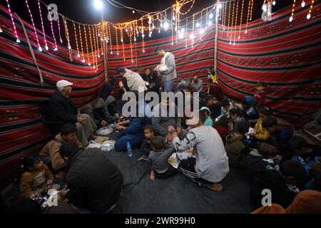 Rafah, Gaza. 11 mars 2024. Les Palestiniens déplacés ont un dîner de rupture rapide (iftar) au milieu de tentes de fortune dans le camp de réfugiés de Rafah, le premier jour du Ramadan du mois sacré des musulmans à Rafah, Gaza, le 11 mars 2024. Photo de Ismael Mohamad/UPI crédit : UPI/Alamy Live News Banque D'Images