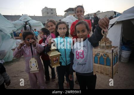 Rafah, Gaza. 11 mars 2024. Des enfants palestiniens déplacés portent des lanternes traditionnelles « fanous » au milieu de tentations de fortune pendant les célébrations du début du mois de jeûne sacré musulman du Ramadan à Rafah, en Ontario, dans le sud de la bande de Gaza, le lundi 11 mars 2024. Photo de Ismael Mohamad/UPI. Crédit : UPI/Alamy Live News Banque D'Images