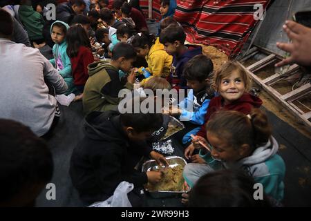 Rafah, Gaza. 11 mars 2024. Les Palestiniens déplacés ont un dîner de rupture rapide (iftar) au milieu de tentes de fortune dans le camp de réfugiés de Rafah, le premier jour du Ramadan du mois sacré des musulmans à Rafah, Gaza, le 11 mars 2024. Photo de Ismael Mohamad/UPI crédit : UPI/Alamy Live News Banque D'Images