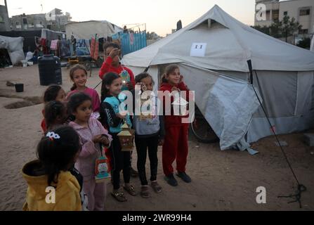 Rafah, Gaza. 11 mars 2024. Des enfants palestiniens déplacés portent des lanternes traditionnelles « fanous » au milieu de tentations de fortune pendant les célébrations du début du mois de jeûne sacré musulman du Ramadan à Rafah, en Ontario, dans le sud de la bande de Gaza, le lundi 11 mars 2024. Photo de Ismael Mohamad/UPI. Crédit : UPI/Alamy Live News Banque D'Images