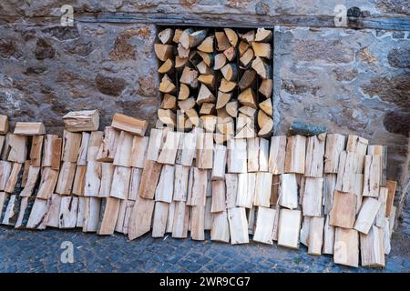 Charme rustique. Bois de chauffage empilé, contre fond de mur de pierre. Banque D'Images