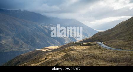 Les voitures passant la route sinueuse menant à travers les montagnes passent dans l'environnement alpin, Nouvelle-Zélande. Banque D'Images